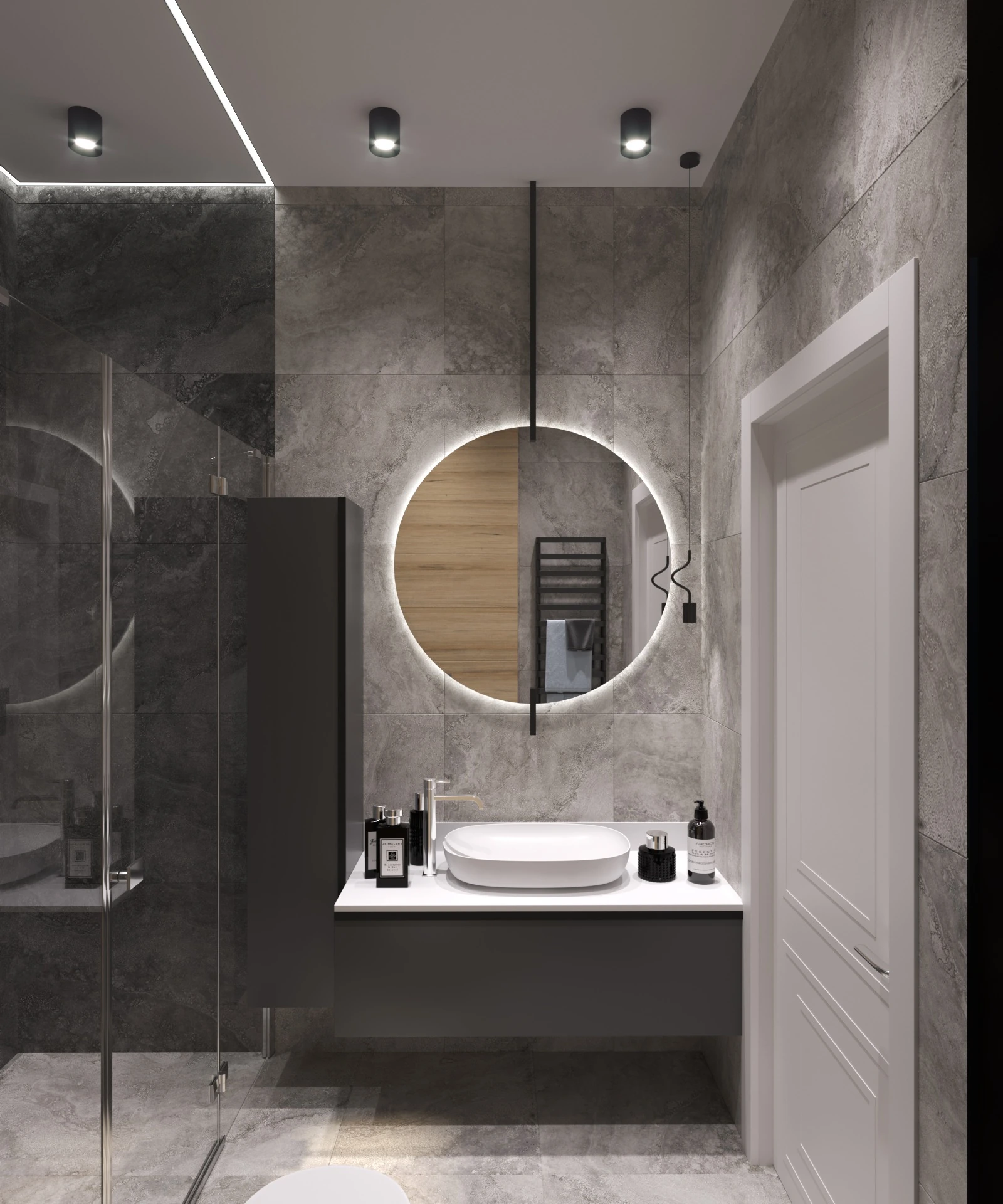 Vanity and illuminated round mirror beside a glass shower enclosure with stone-look finishes